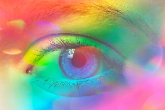 a human eye covered by a transparent layer of rainbow colors