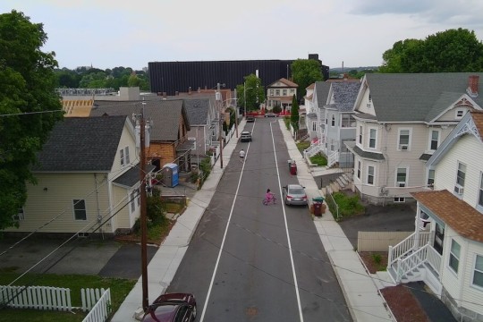 a typical suburban street is shown in an arial view with a large data center looming in the background