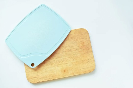 a plastic and a wood cutting board sit next to each other on a white background