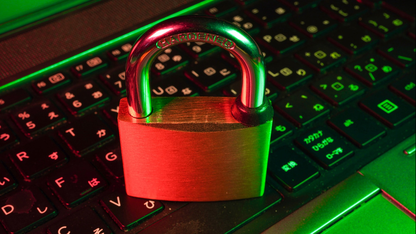 A red metallic padlock on a computer keyboard illuminated by green and red lights, symbolizing cybersecurity.