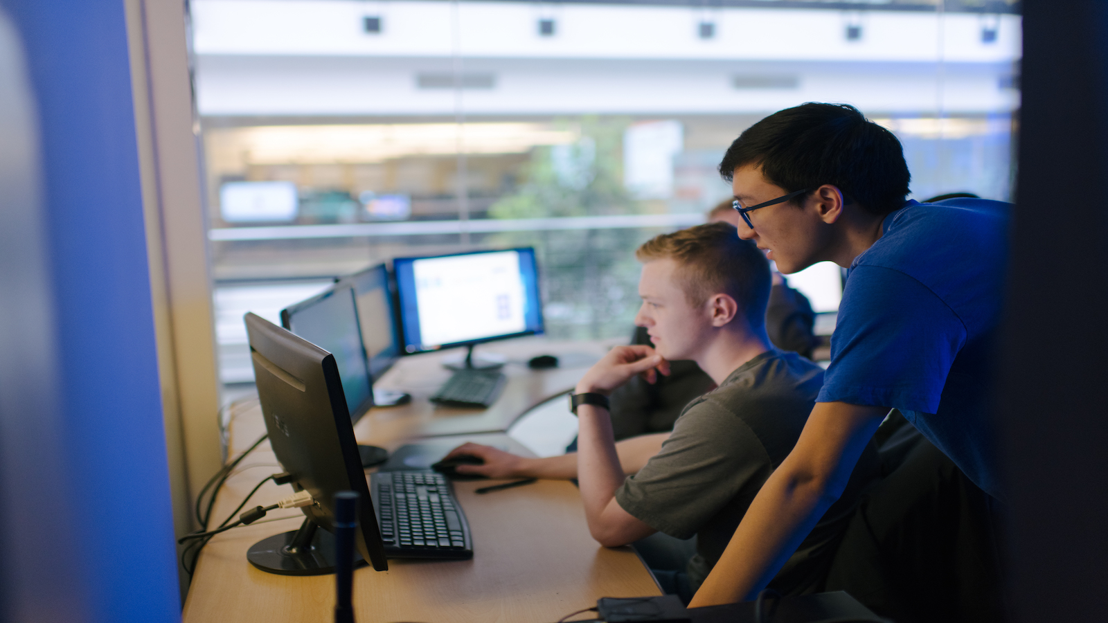 A candid photo of two students looking at a computer.