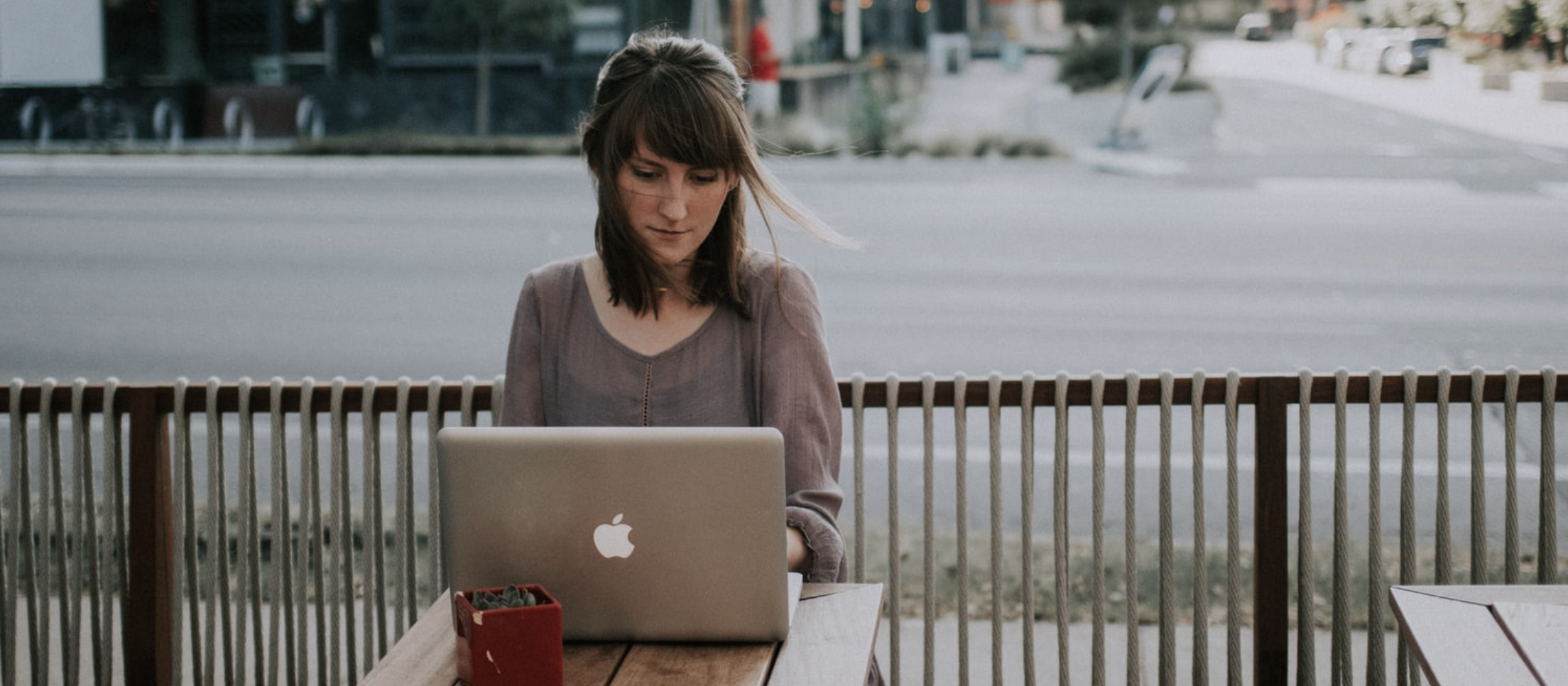 Woman in grey shirt using Mac laptop at a coffee shop