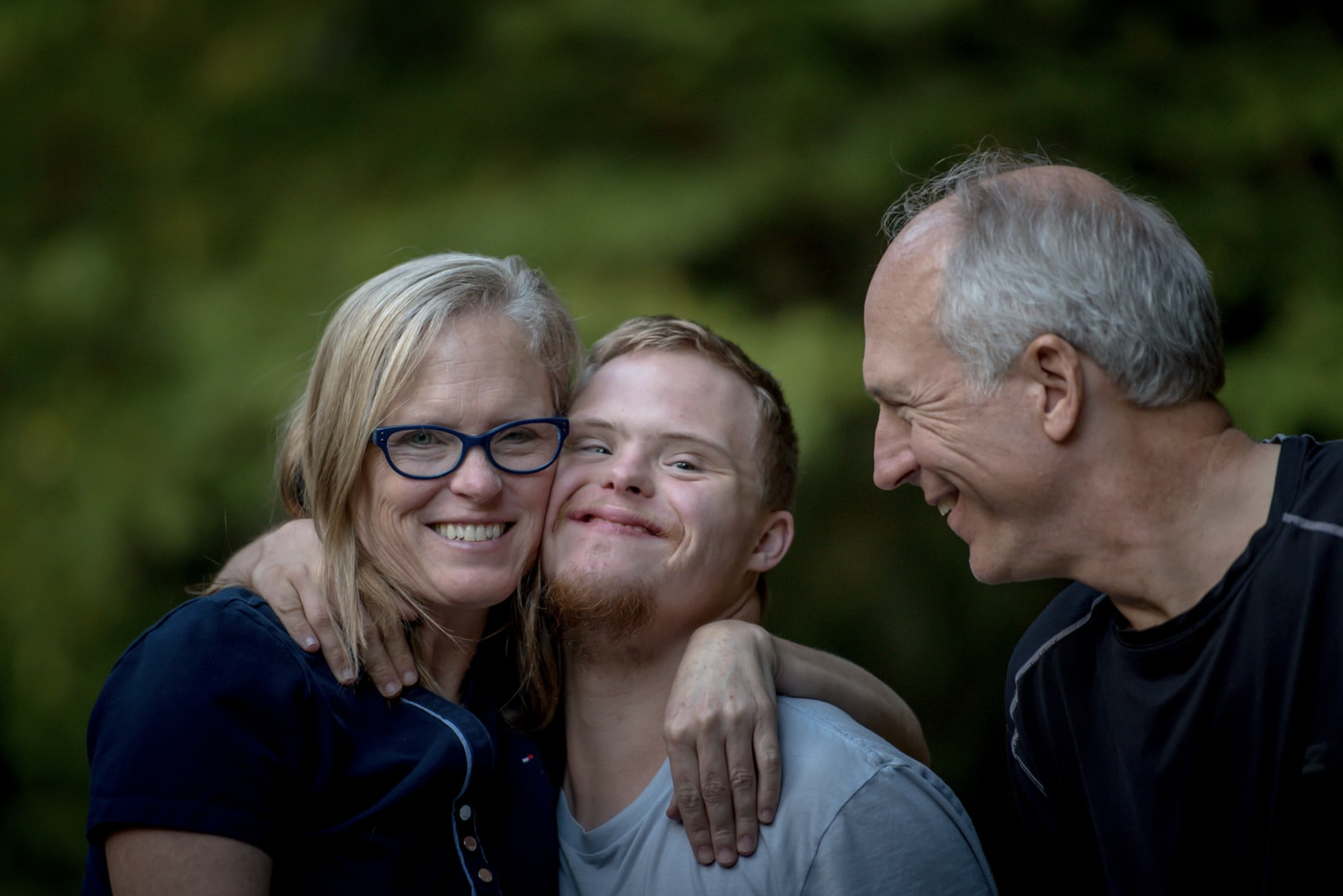 A family with two men and one woman hugging and posing for a picture