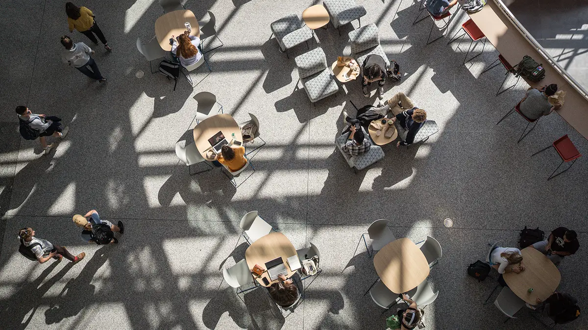 A view from above of students sitting on couches and at tables in the SHED.