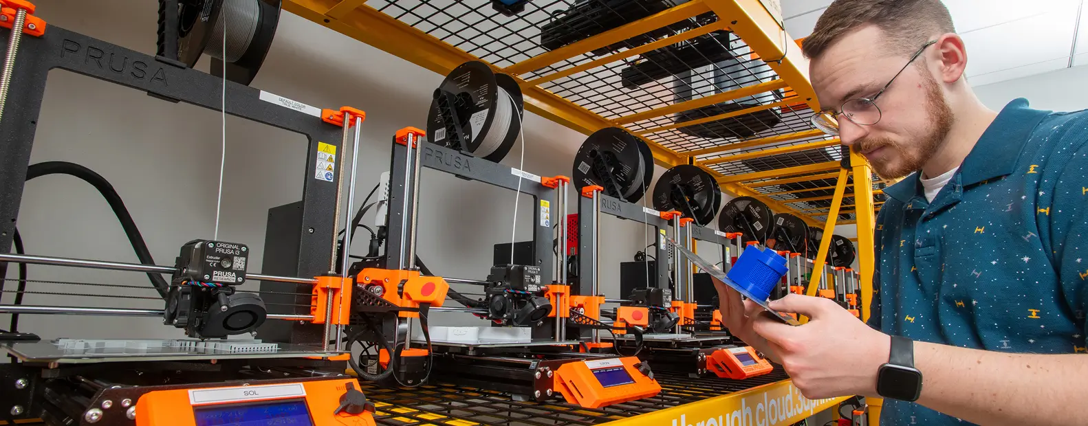A person looking at a print that just completed on a 3D printer.
