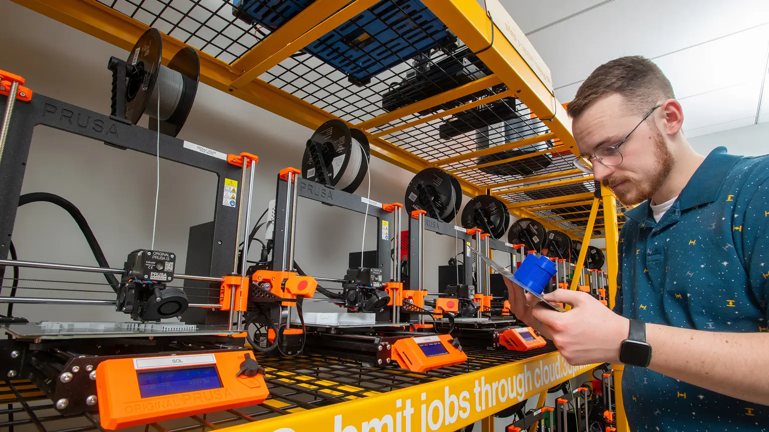 A student grabbing a finished print off of a 3D printer.