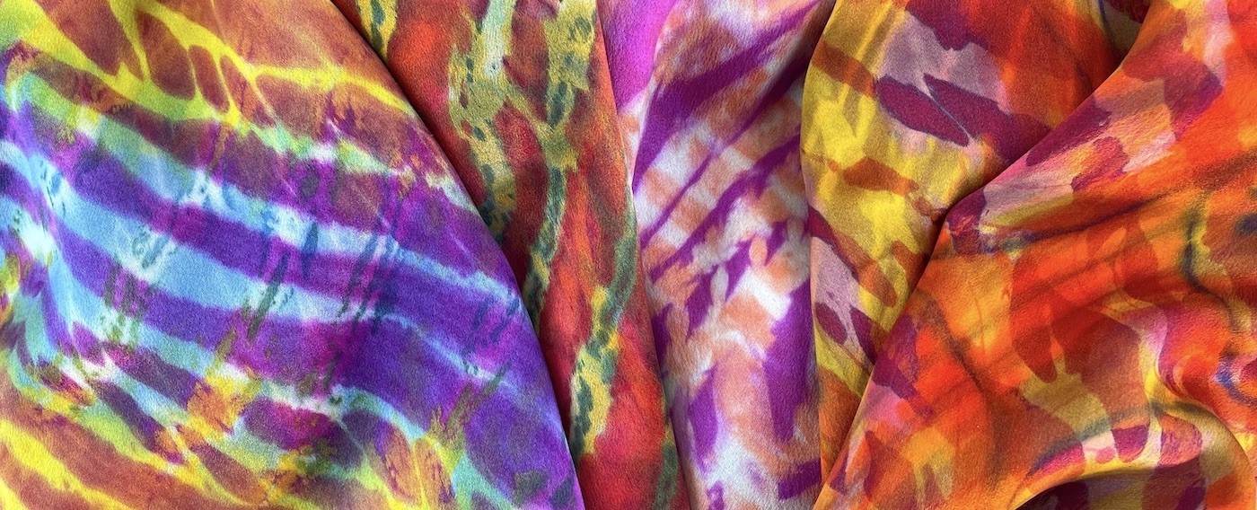 a stack of folded silk scarves with bright striations of color.