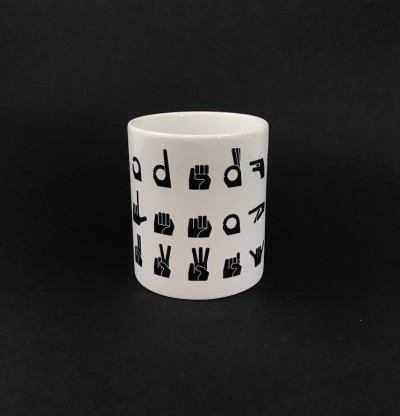 Coffee mug with graphic representations of American Sign Language letter signs.