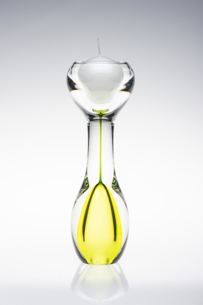 An hourglass shaped clear glass candle holder with lime green inside the bottom of the hourglass shape.