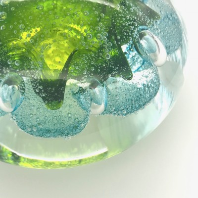 close up of a Handblown clear Glass orb with bubbly lime and blue organic shape inside.