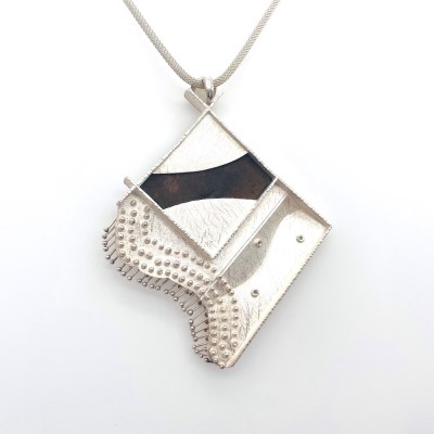 back view of a sculptural pendant on braided silver chain.