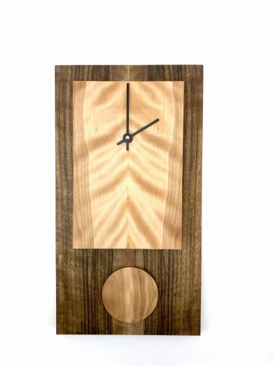 Rectangular clock with dark body and light face with short pendulum made from wood.