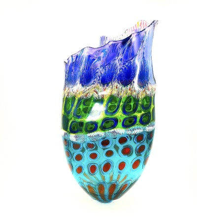 a tall open glass vessel with a ruffled and uneven top edge. Multi colora and patterns are arranged in layers.