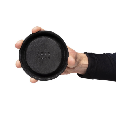 Hand holding round black cast iron tray.