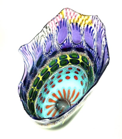 an arial view into the opening of a tall open glass vessel with a ruffled and uneven top edge. Multi colora and patterns are arranged in layers.