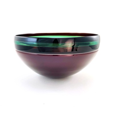 a glass bowl with a smooth surface and dark purple base, black band around the rim with a bright green accent stripe.