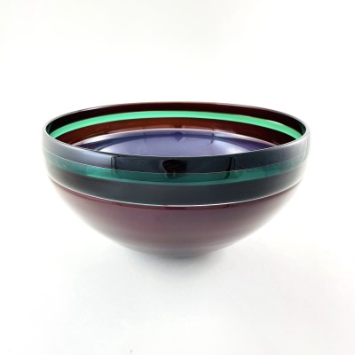 a glass bowl with a smooth surface and dark purple base, black band around the rim with a bright green accent stripe.