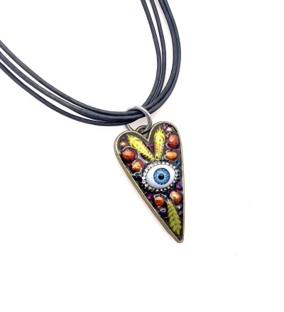 a heart shaped pendant with a cluster of beads and glass blue eye encased in acrylic.