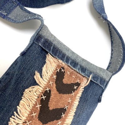 a handsewn blue jean fabric shoulder bag with strips of brown and black chevron patterned African mudcloth..