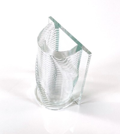 a clear glass vase with a ribbed textural round half and a flat side.