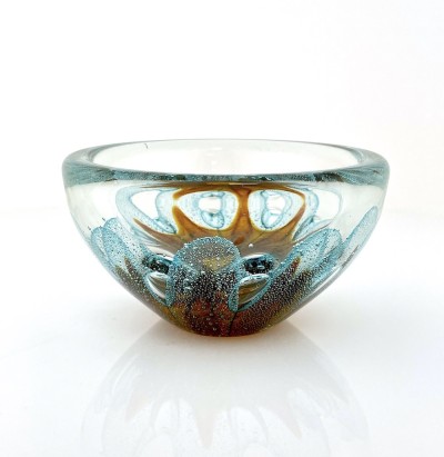 a round clear glass bowl with a starfish like gold design in the center with air bubbles around it.