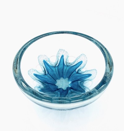 a round clear glass bowl with a starfish like teal design in the center with air bubbles around it.
