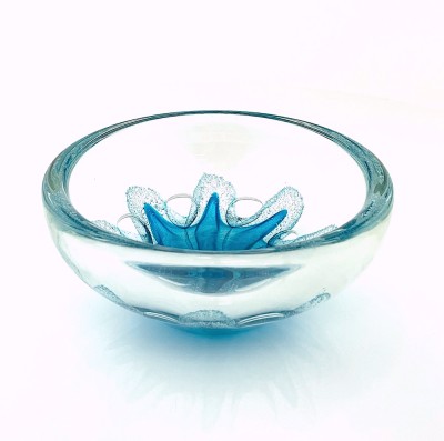 a round clear glass bowl with a starfish like teal design in the center with air bubbles around it.