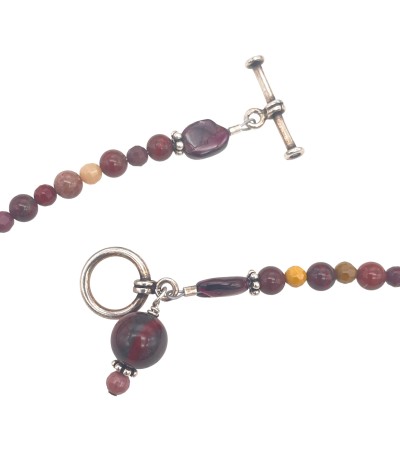 a necklace of strung desert-hued polished round beads with small silver charms and a toggle clasp.