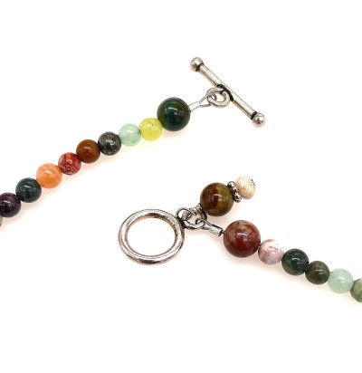 a detail of a necklace of strung smoky-hued polished round beads with small silver charms and a toggle clasp.