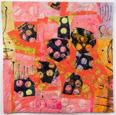 a painterly fabric quilt with a cluster of bulbous black and white dotted forms floating on a coral pink background.