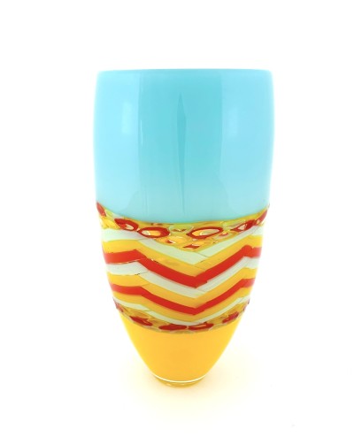 a tall, narrow glass vase with a turquoise top band, a red and yellow chevron colored central band and a yellow base.