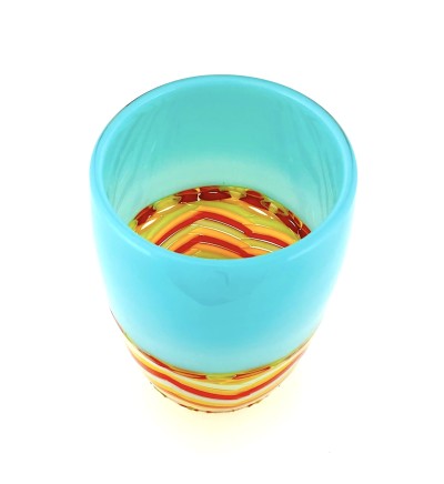 a tall, narrow glass vase with a turquoise top band, a red and yellow chevron colored central band and a yellow base.