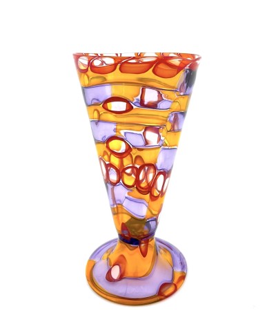 a glass footed cup with a complex pattern of layered, swirly bands of transluscent colors from orange to circles of red and bands of purple.