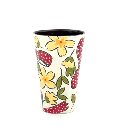 a ceramic tumbler with a white base and illustration of flowers and red bows.