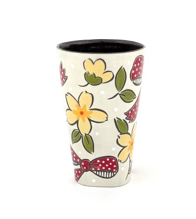 a ceramic tumbler with a white base and illustration of flowers and red bows.