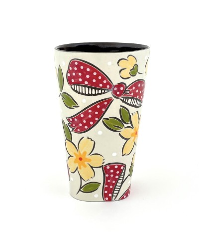 a ceramic tumbler with a white base and illustration of flowers and red bows.