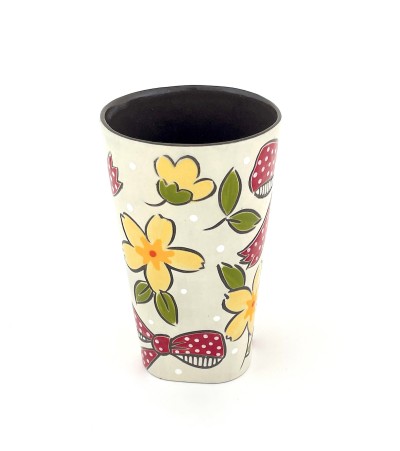 a ceramic tumbler with a white base and illustration of flowers and red bows.
