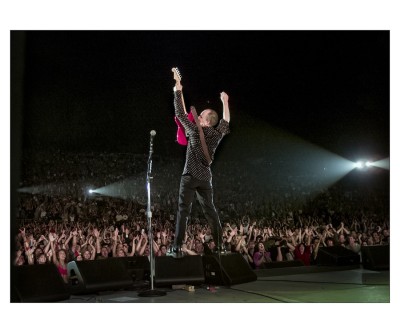 a color photograph of musician Pete Townshend on stage with arms uplifted.