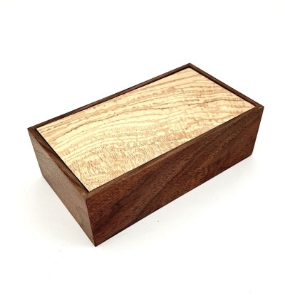 a handmade rectangular walnut box with a light applewood lid.