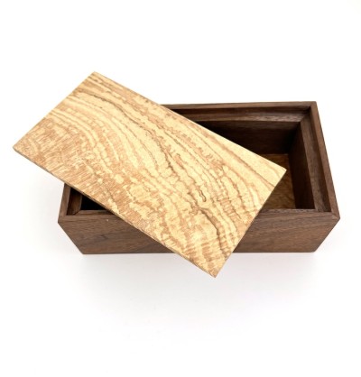 a handmade rectangular walnut box with a light applewood lid.