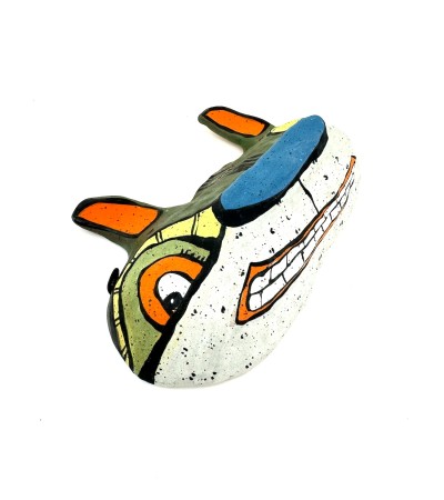 a hand sculpted ceramic mask form of a wide cat like face with orange ears, a blue nose, and a toothy smile.
