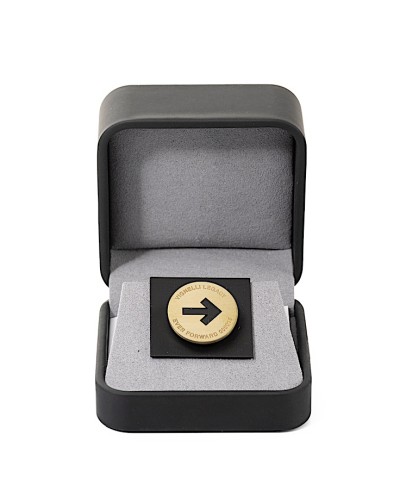 a small round brass token in a presentation box.