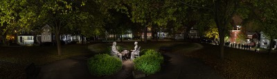 a nighttime photo of two broad sculpture figures facing each other other sharing tea.