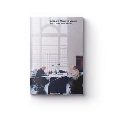 a book cover showing Lella and Massimo Vignelli working across from each other with the title 'Lella and Massimo Vignelli: Two Lives, One Vision' at the top in black font.