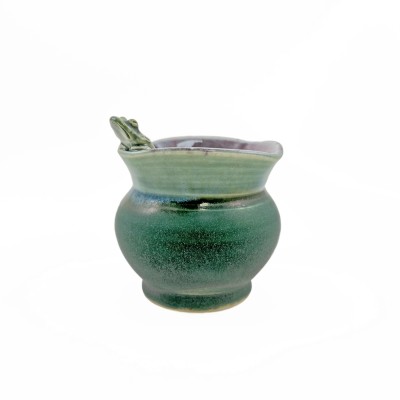 Side view of small bud vase with square rim, burgundy interior, green exterior glaze, and a small frog perched on the rim