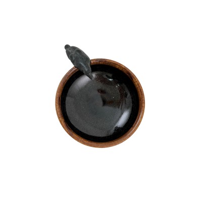 Top view of a small bowl with green hues and a brown interior, with a small black crow on the rim