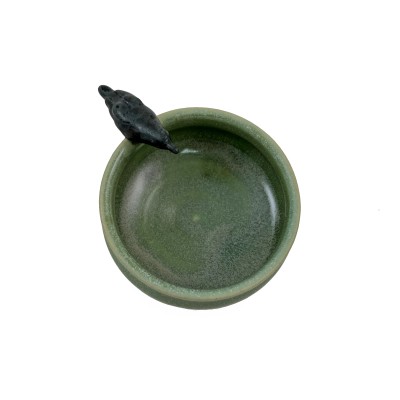 Top view of small light green bowl with a small black crow on the rim