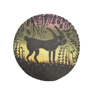 a circle sculpture plate with a sunset in the background and a bunny and plants in the foreground painted in black and details created by carving