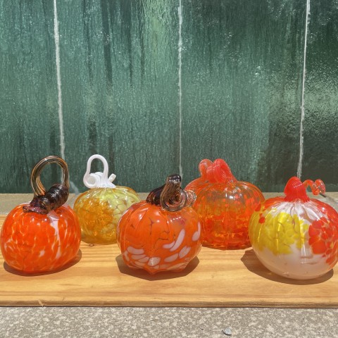 a group of five orange glass pumpkins in front of a green glass water wall.