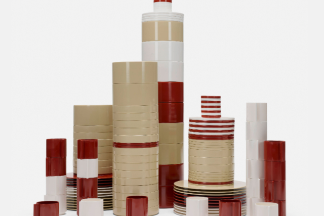 Multiple stacks of white, red, and ivory melamine dishes and bowls that create a sculptural layout (image from the front).